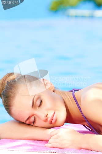 Image of Woman sleeping next to swimming pool