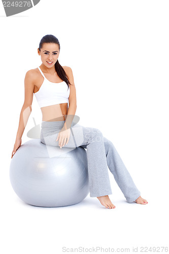 Image of Athletic woman relaxing on fitness ball