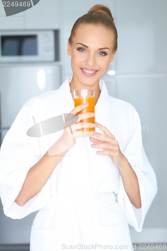 Image of Woman in bath robe drinking orange juice