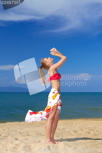 Image of Joyful woman with arms raised at the beach