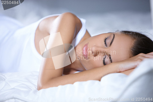 Image of Beautiful woman is resting on white bed