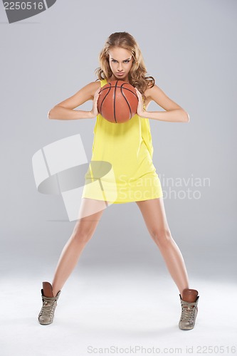 Image of Young blond woman posing and holding basket ball