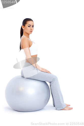 Image of Athletic woman relaxing on fitness ball