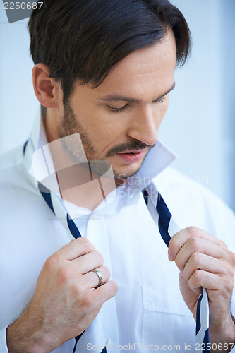 Image of Man putting on his tie