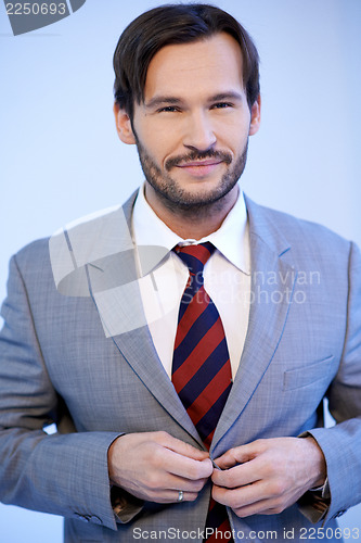 Image of Smiling businessman buttoning his jacket