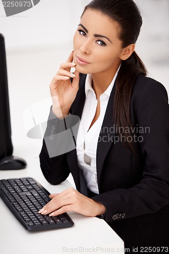 Image of Woman in black suit sitting in front of computer