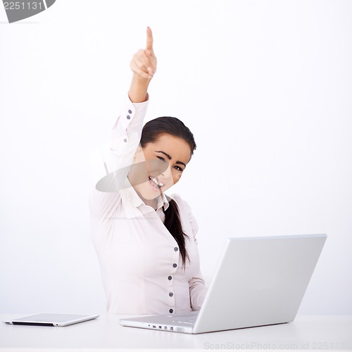 Image of Happy woman sitting at her desk, with one arm rised