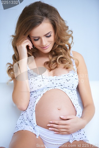 Image of Adorable young pregnant woman looking on her belly