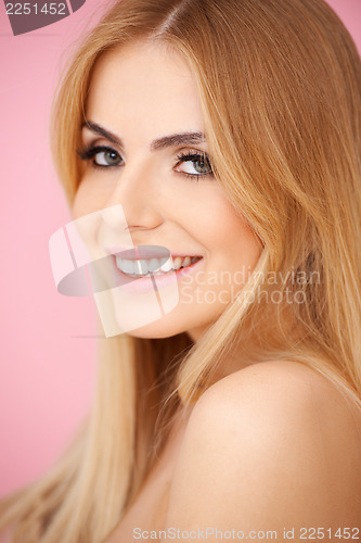 Image of Smiling blond young woman over pink