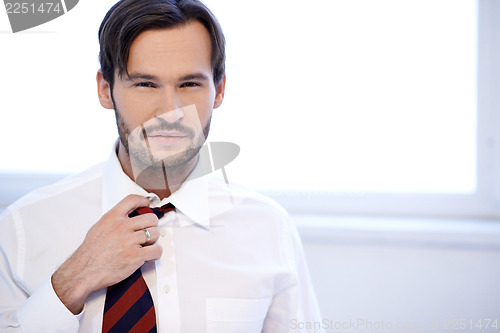 Image of Attractive man adjusting the knot of his tie