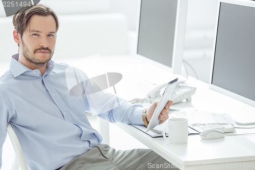 Image of Handsome businessman sitting in front of monitors