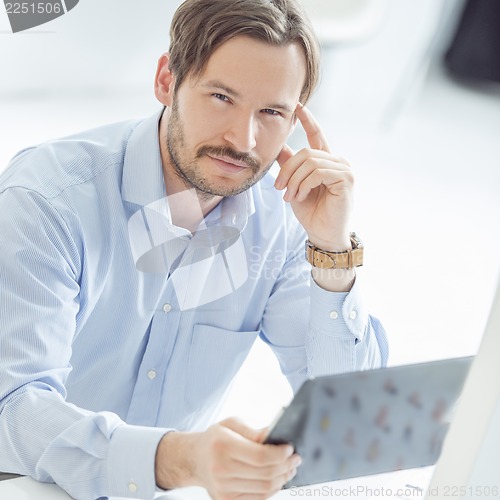 Image of Young hansome businessman sitting at the desk