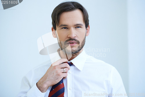 Image of Bearded young man fiddling with his tie