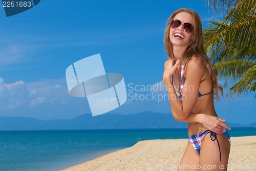 Image of Smiling woman with sunglasses on sandy beach