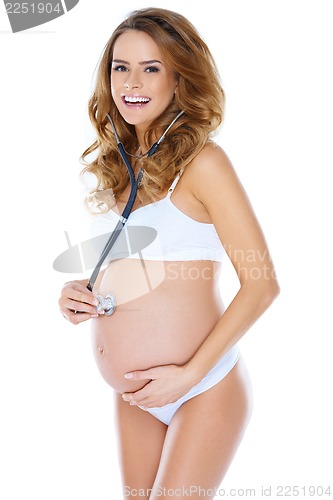 Image of Cute pregnant young woman using stethoscope