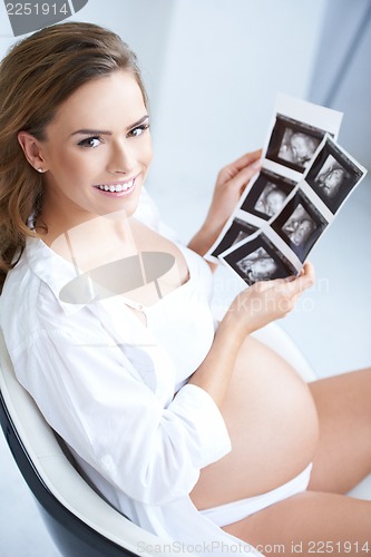 Image of Pregnant woman holding her USG pictures