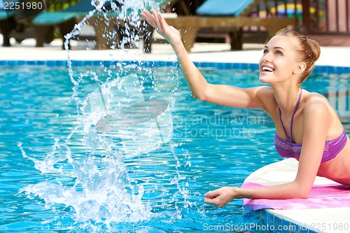 Image of Happy woman splashing water in pool
