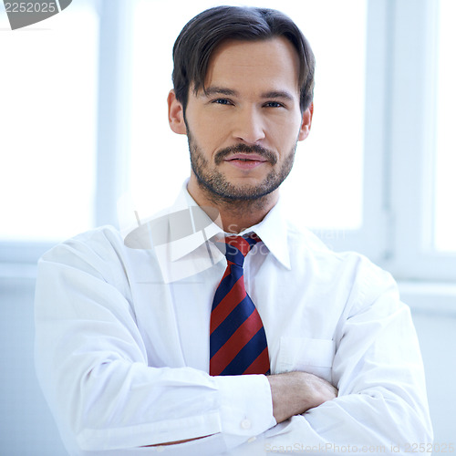 Image of Handsome man standing with folded arms