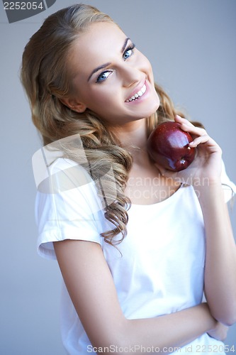Image of Head shot of woman holding red apple against grey