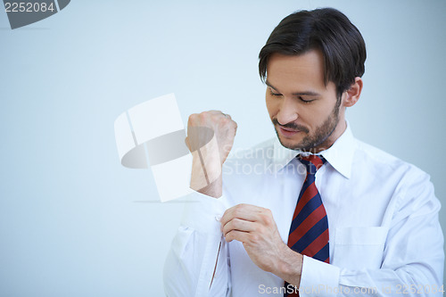 Image of Young man buttoning his cuffs