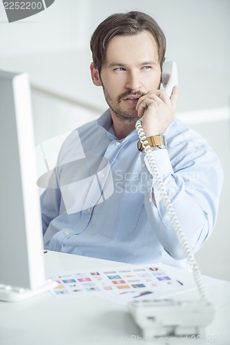 Image of Busy businessman talking phone at his desk