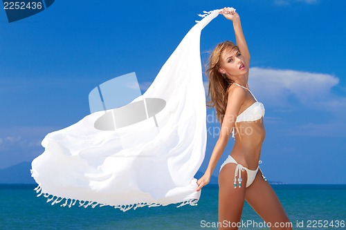 Image of Attractive woman in white bikini holding scarf