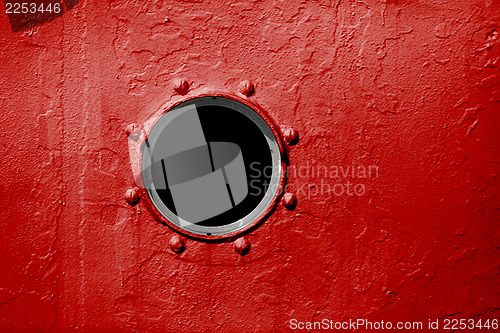 Image of Porthole on red wall of old ship