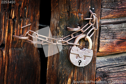 Image of Old rusty padlock on rural wooden gate