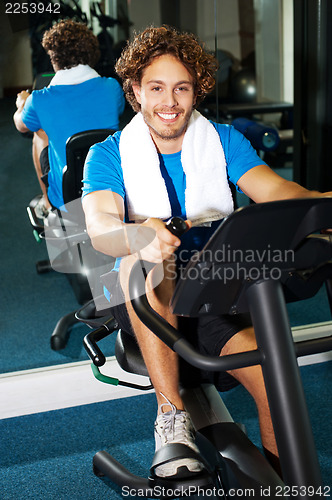 Image of Handsome man at the gym doing static cycling