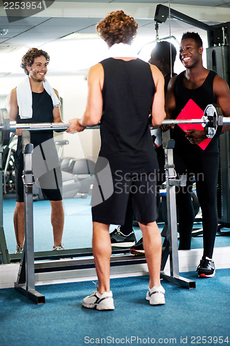 Image of Smart young guy lifting barbells in gym