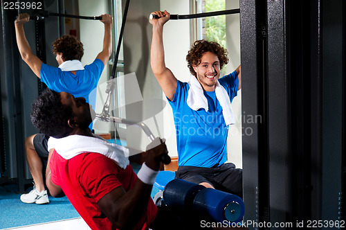 Image of Strong young guys toning their upper body in gym