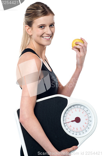 Image of Fit girl holding fruit and weighing scale