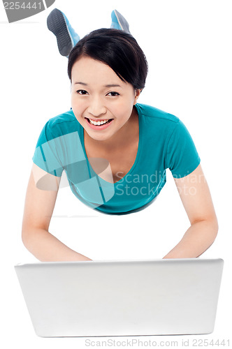 Image of Girl lying on the studio floor and using laptop