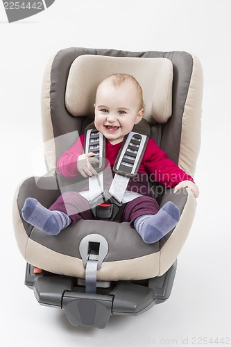Image of happy child in booster seat for a car in light background