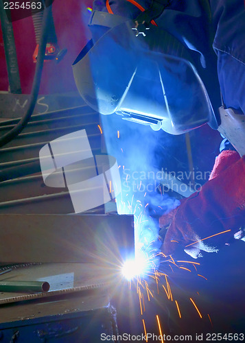 Image of welder with protective mask welding metal and sparks