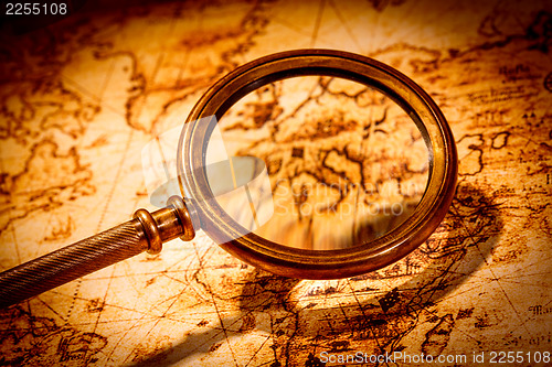 Image of Vintage magnifying glass lies on an ancient world map