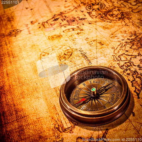 Image of Vintage compass lies on an ancient world map.