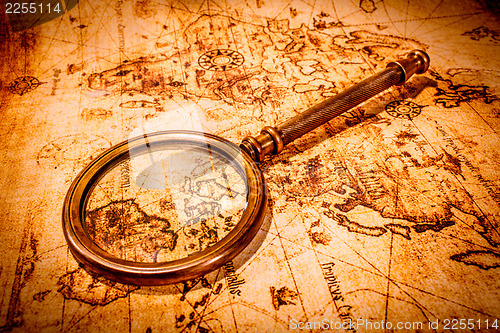 Image of Vintage magnifying glass lies on an ancient world map