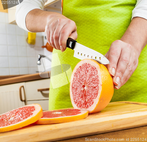 Image of Woman's hands cutting grapefruit