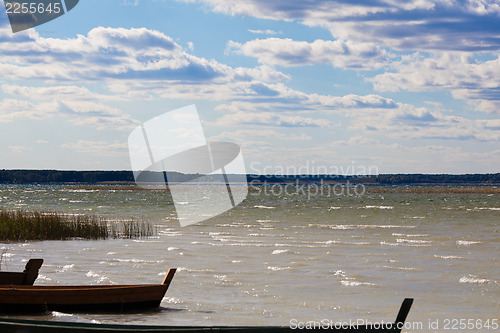 Image of Majestic cloudscape and stationary boats at lakeside