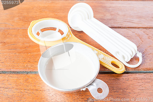 Image of Beginning step of bakery preparation with milk, spoon and yolk s