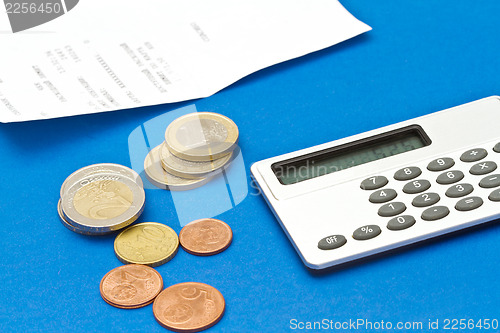 Image of Several euro coins, bill and calculator on blue background