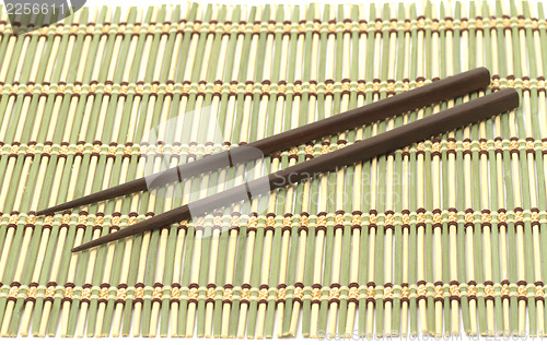 Image of Dark wooden chopsticks on bamboo mat