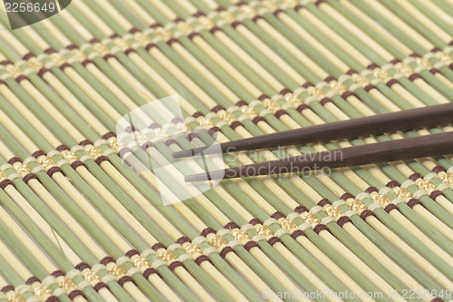 Image of Dark wooden chopsticks on bamboo mat