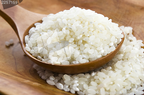 Image of Rice in wooden spoon on kitchen table