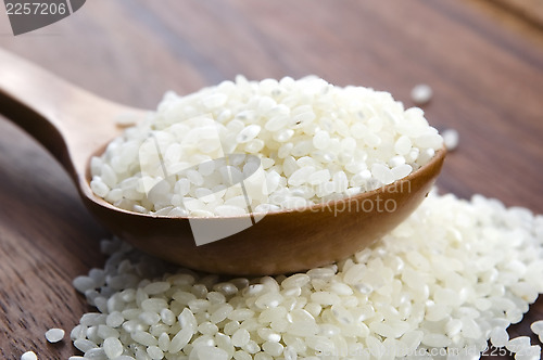 Image of Rice in wooden spoon on kitchen table