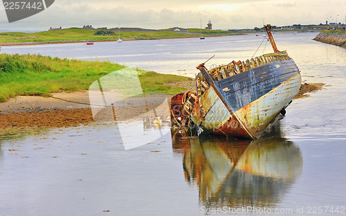 Image of boat wreck lying on the shore of lake