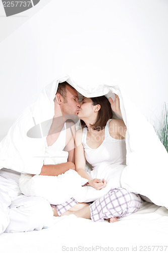 Image of Couple kissing under the bedclothes