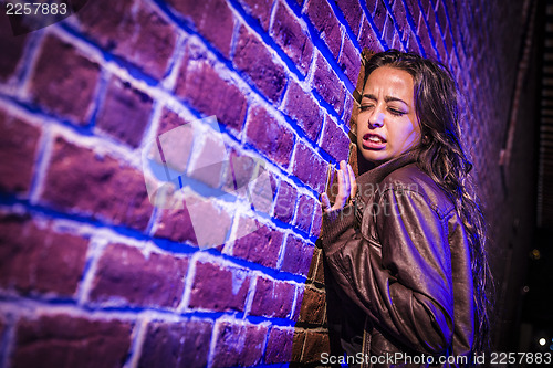 Image of Frightened Pretty Young Woman Against Brick Wall at Night