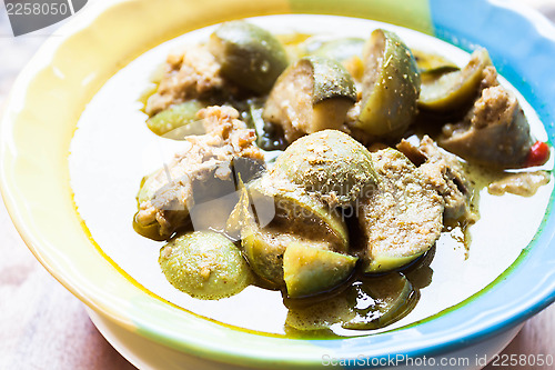 Image of A bowl of spicy green curry with chicken and eggplant